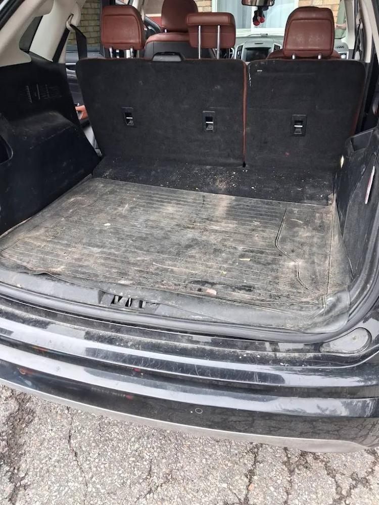 The same SUV cargo area before detailing, covered in dirt, dust and debris